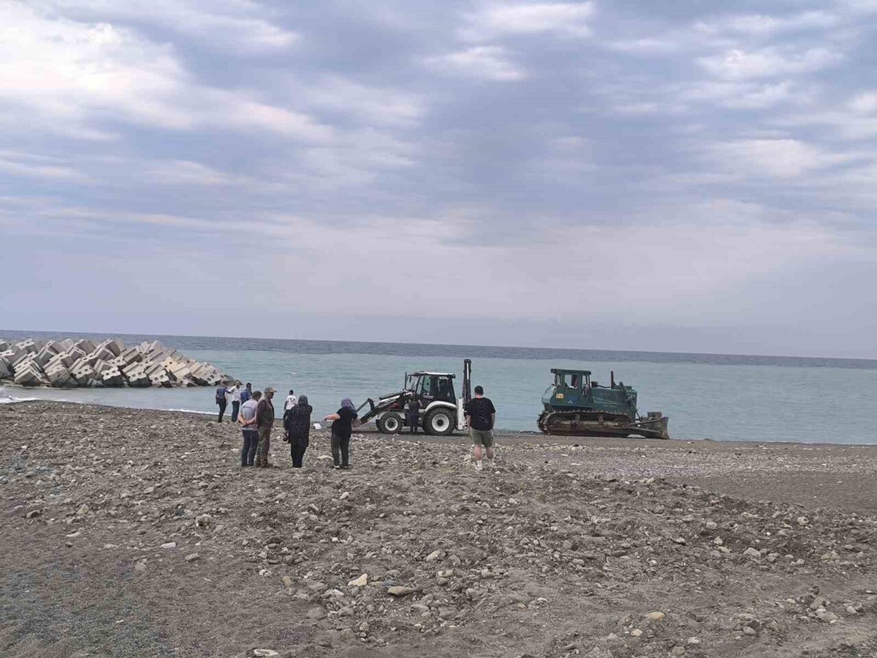 Kastamonu’nun Abana ilçesinde sahilde dinlenen kadın, temizlik yapan iş makinesinin